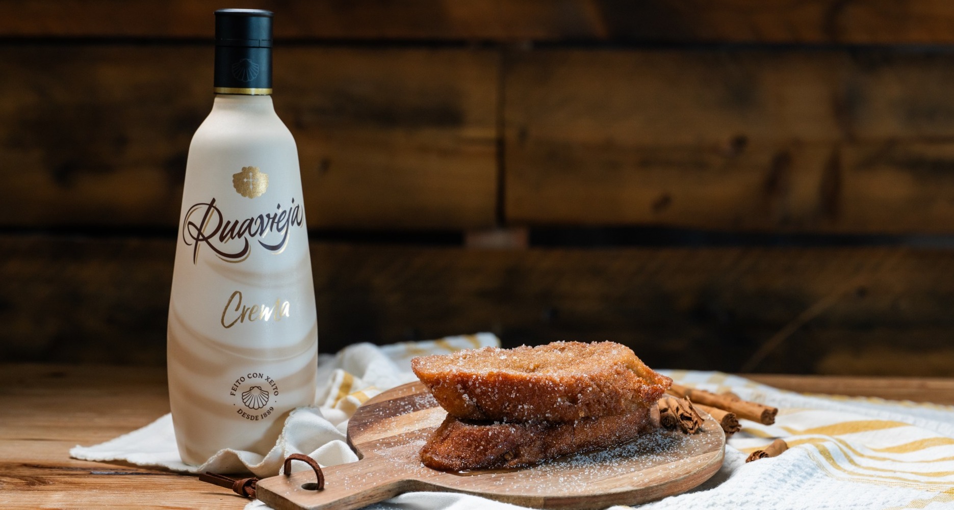 nueva torrija de Levaduramadre con crema Ruavieja, sobre una tabla y junto a una botella de la bebida
