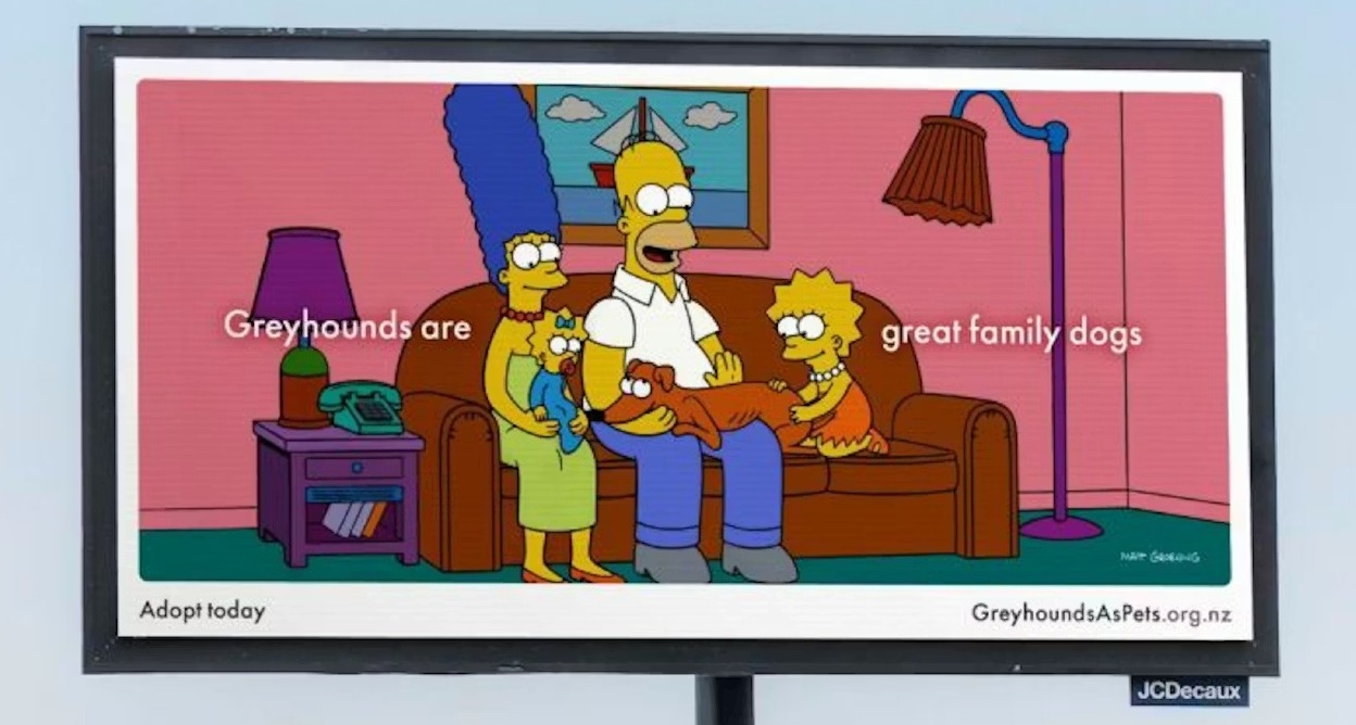 Los Simpson sentados en el sofá abrazando a su galgo