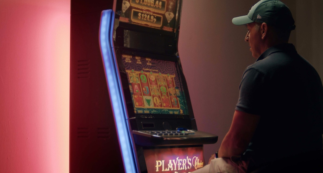 Un señor sentado jugando en una máquina tragaperras