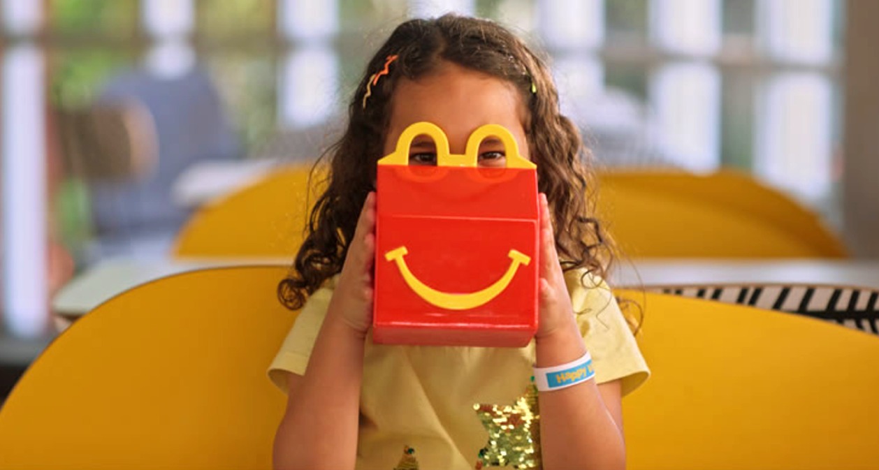Una niña mirando por los arcos amarillos de la caja del Happy Meal