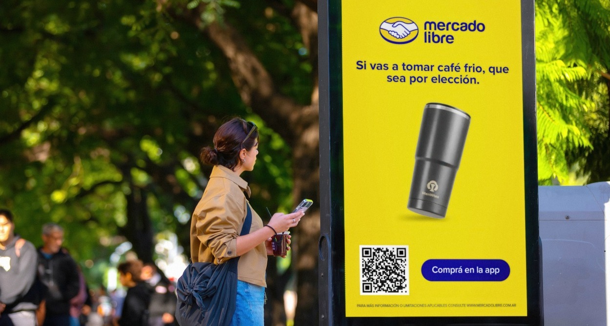 Una chica se detiene ante el mupi de Mercado Libre para leer el mensaje