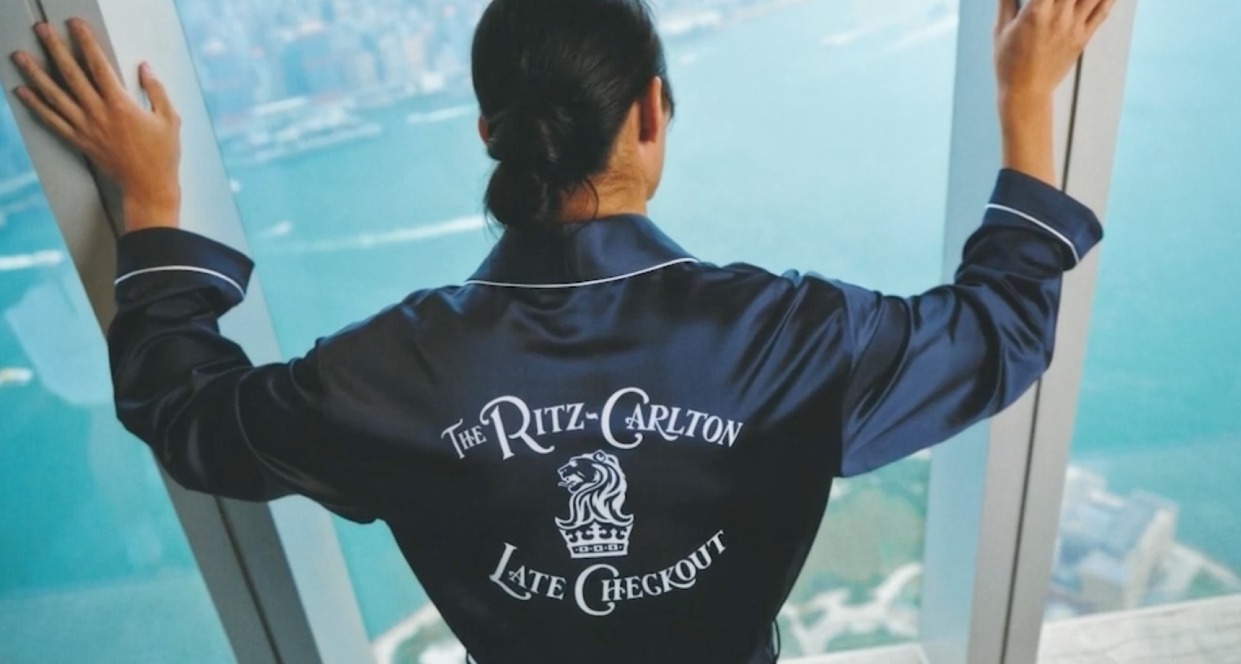 una mujer mira por la ventana con la bata del ritz carlton late checkout