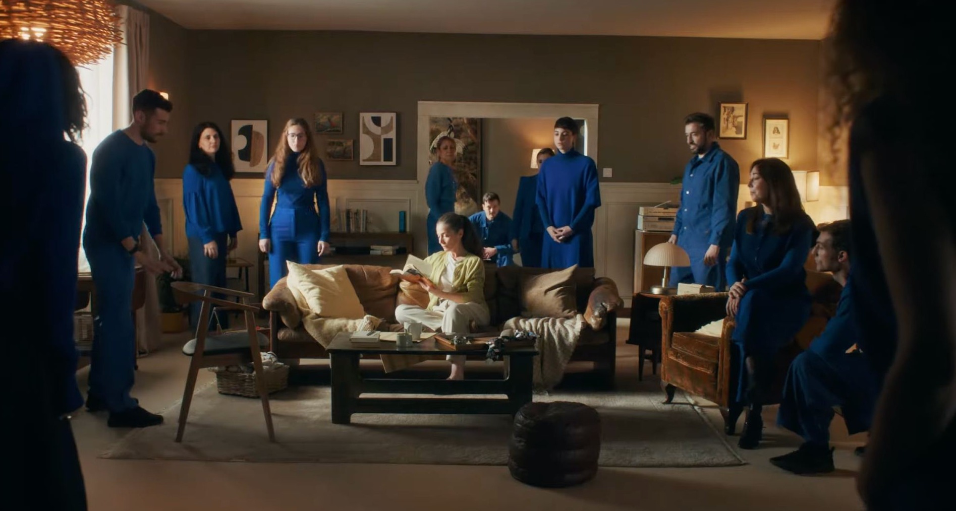 Personas vestidas de azul en torno a una mujer sentada en el sofá