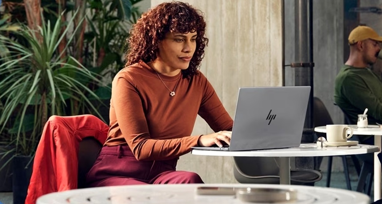 HP entra en el negocio publicitario con su propia red de anuncios y una plataforma de streaming integrada en sus portátiles una mujer trabajando en una cafeteria con su ordenador portatil
