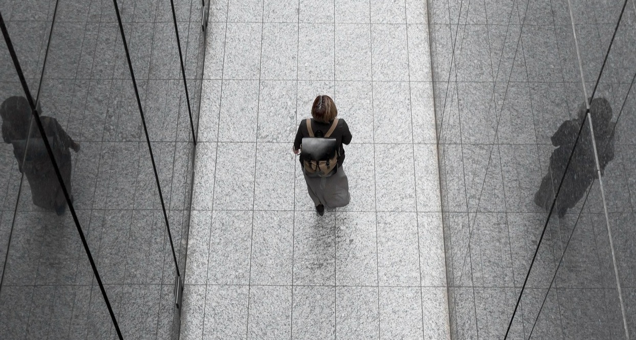 Una mujer caminando por un pasillo de espejos con una mochila de trabajo