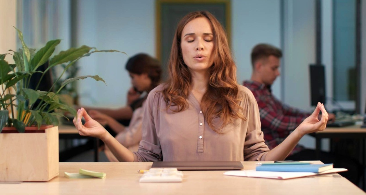Una mujer con gesto de meditación en la oficina