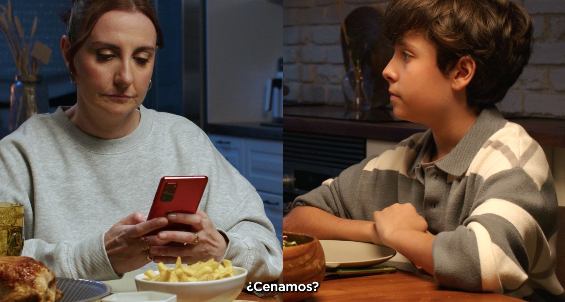 “Saca el móvil de la cena”, la campaña de Unicef y Atresmedia para promover espacios familiares sin dispositivos digitales una madre usa el movil en la mesa mientras su hijo espera mirándola para empezar a cenar