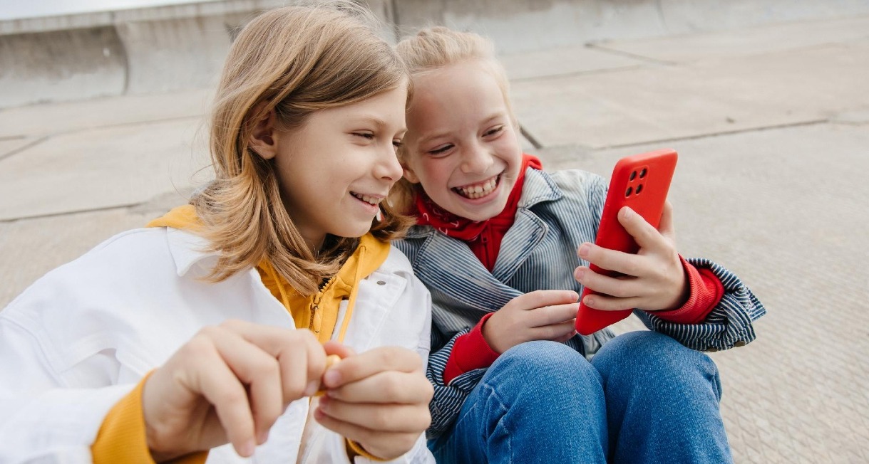 Dos niños mirando un smartphone sonriendo