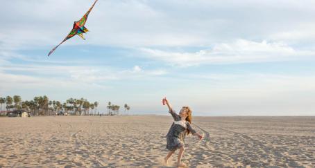 Niña volando una cometa en la playa