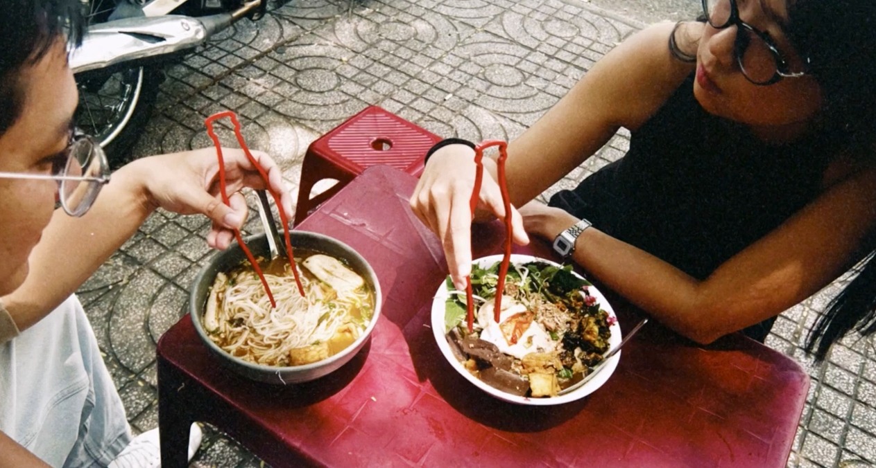 Una pareja comiendo ramen con los palillos rojos de coca-cola