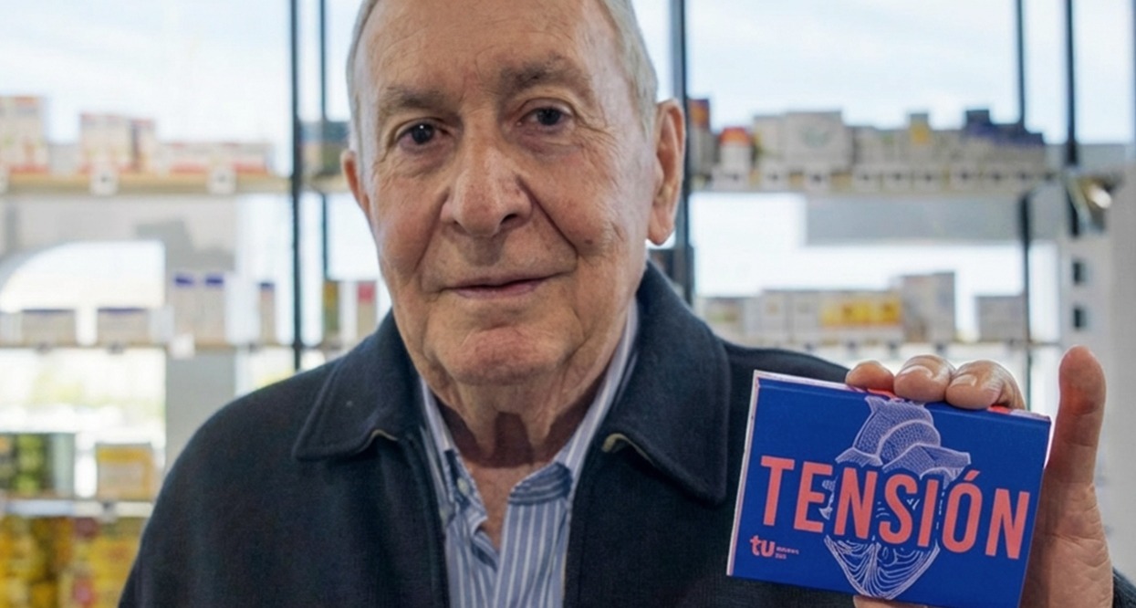 Un hombre mayor muestra una caja de pastillas en la que se lee en grande "Tensión"