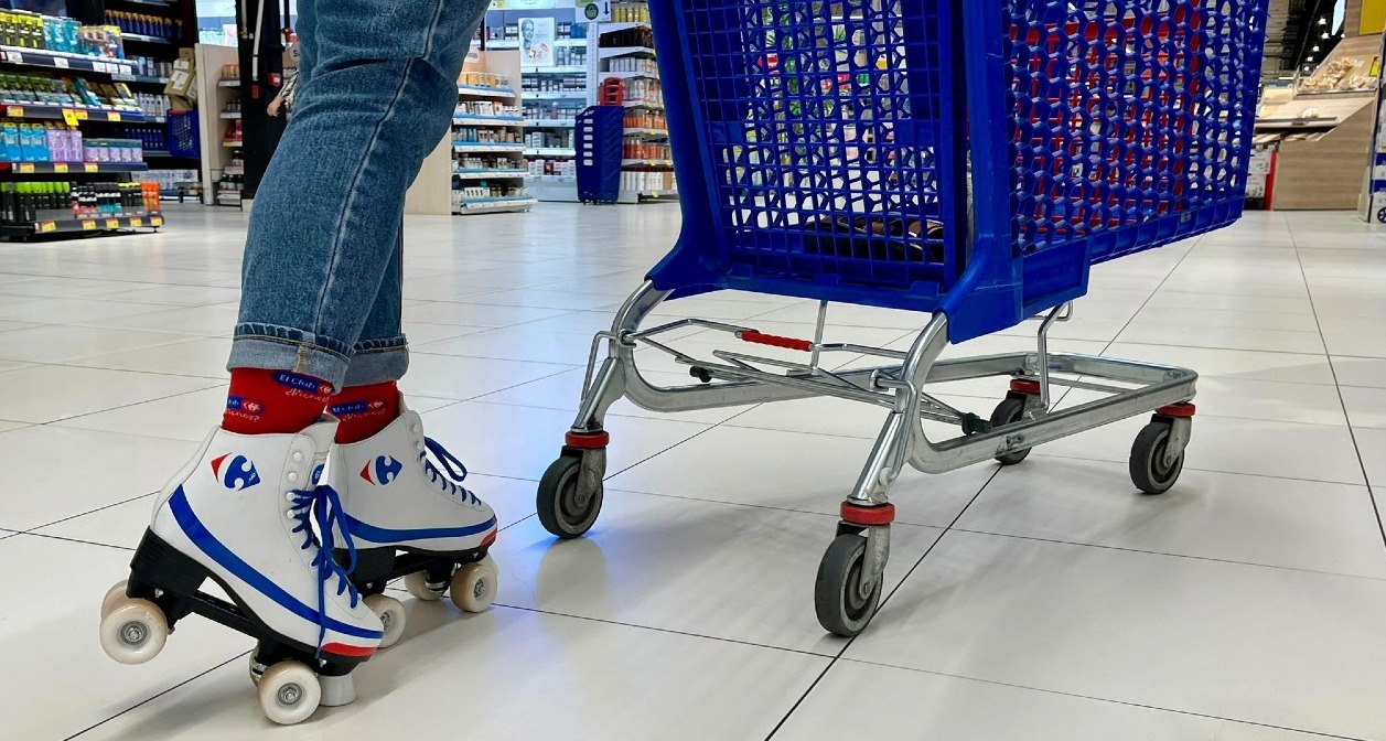 una persona con patines al lado de un carro de la compra en Carrefour