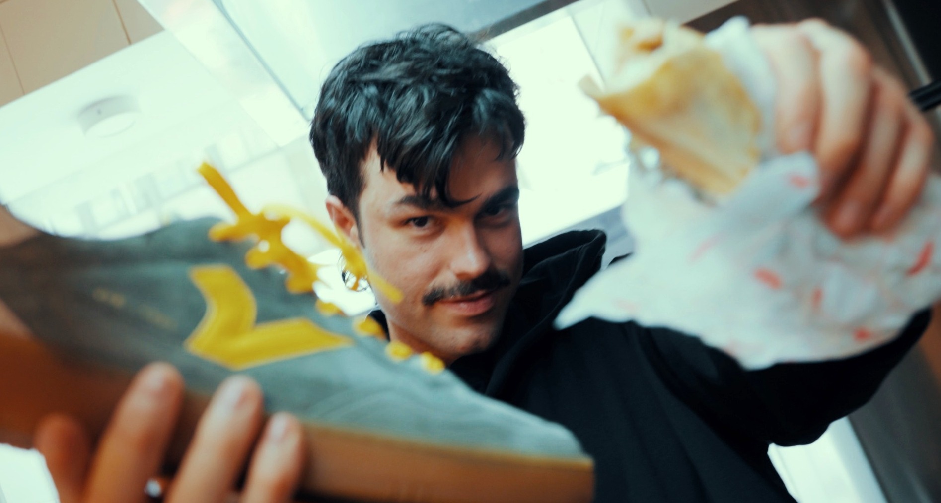 El tiktoker Peldanyos mirando a cámara mientras sujeta con una mano una zapatilla Victoria y con otra un shawarma