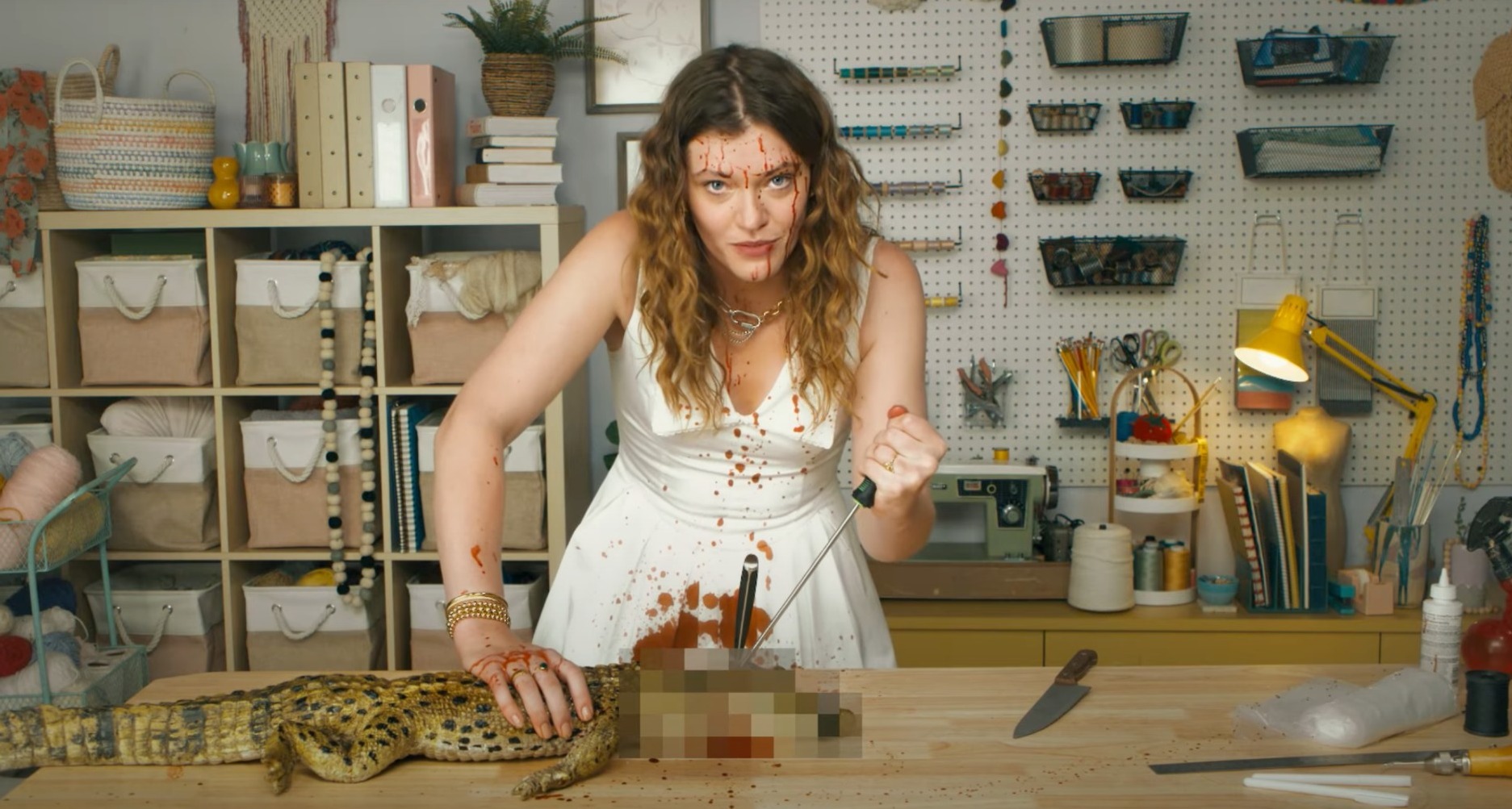 Mujer jóven clavando un cuchillo en la cabeza de un cocodrilo para enseñar a hacer un bolso birkin en la nueva campaña de PETA
