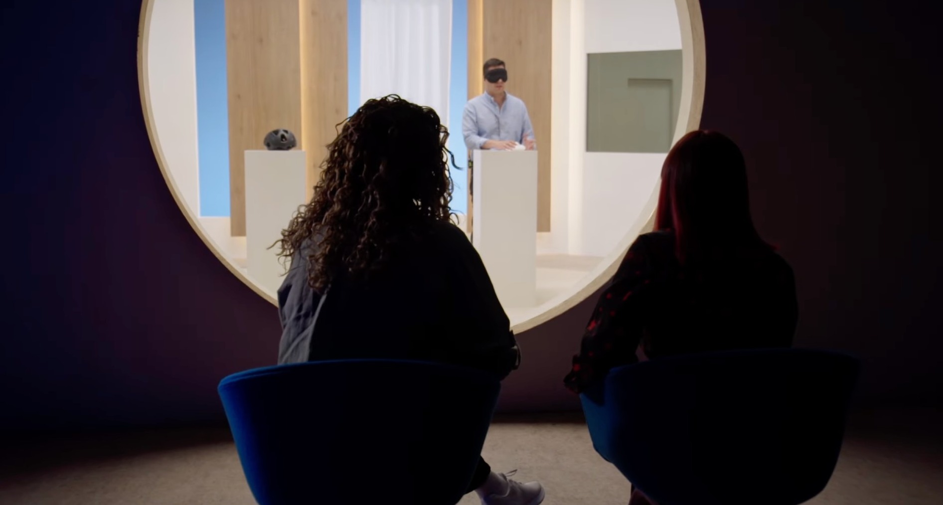 Dos mujeres miran a un hombre a través de una cámara