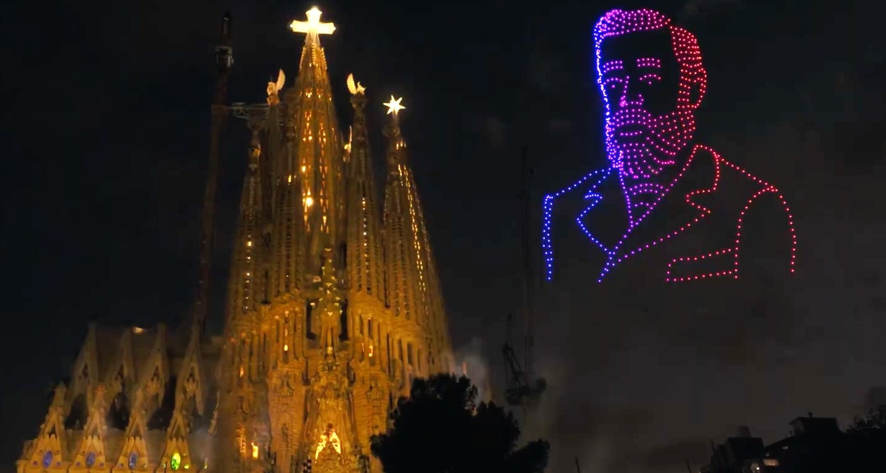 La Sagrada Familia iluminada y la imagen de Gaudí al lado hecha con drones