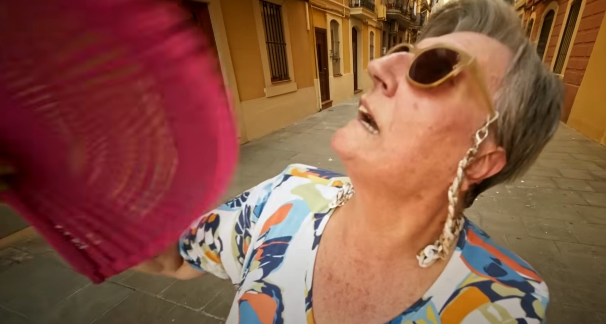una señora abanicándose con expresión de calor