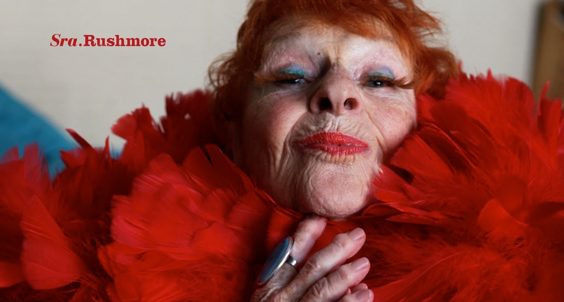 Una mujer mayor pelirroja con plumas rojas