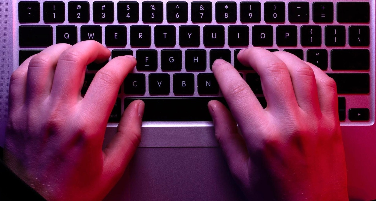 Una manos sobre el teclado de un ordenador portátil