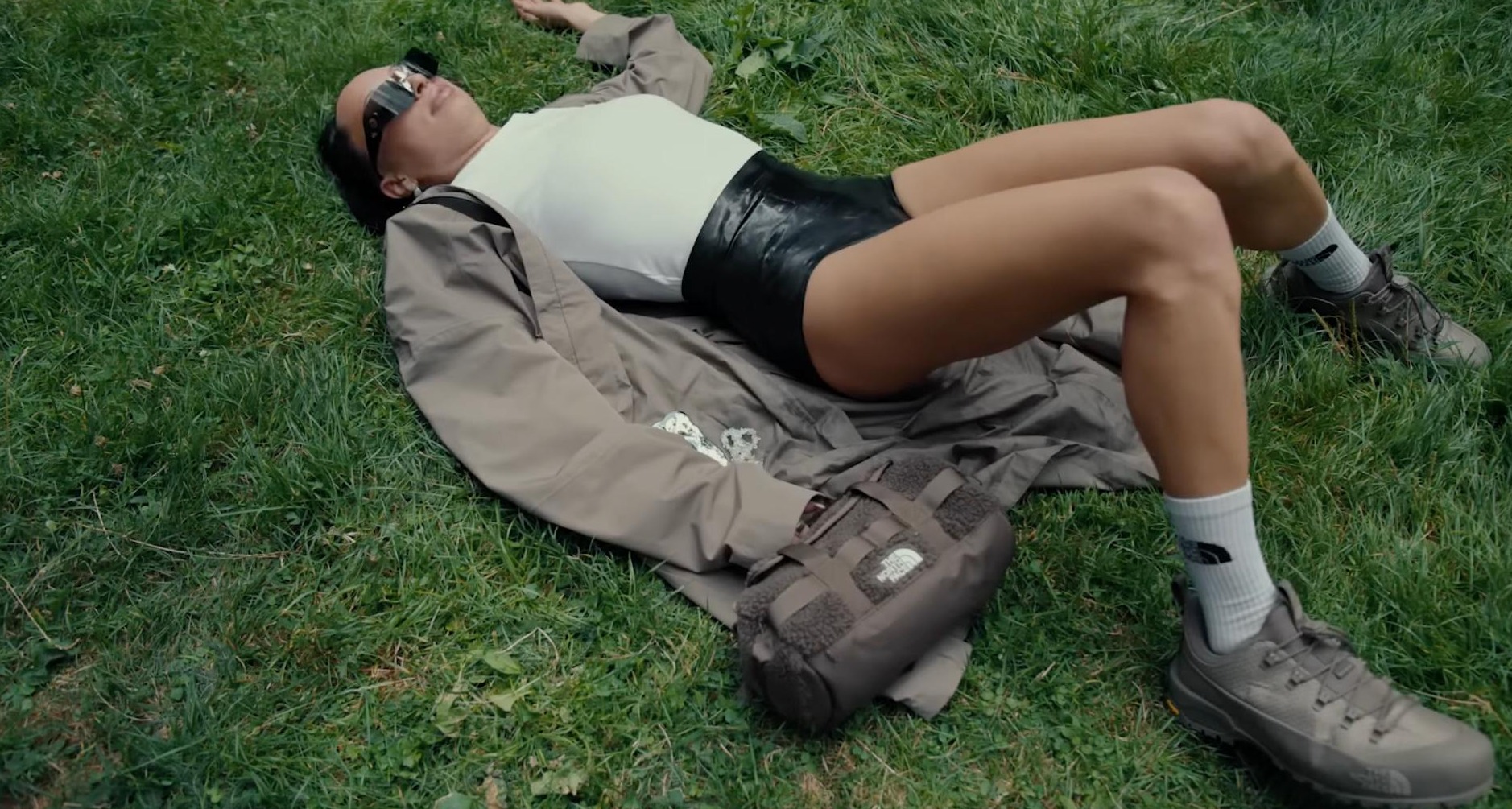 Chica vestida con ropa de The North Face tumbada sobre hierba