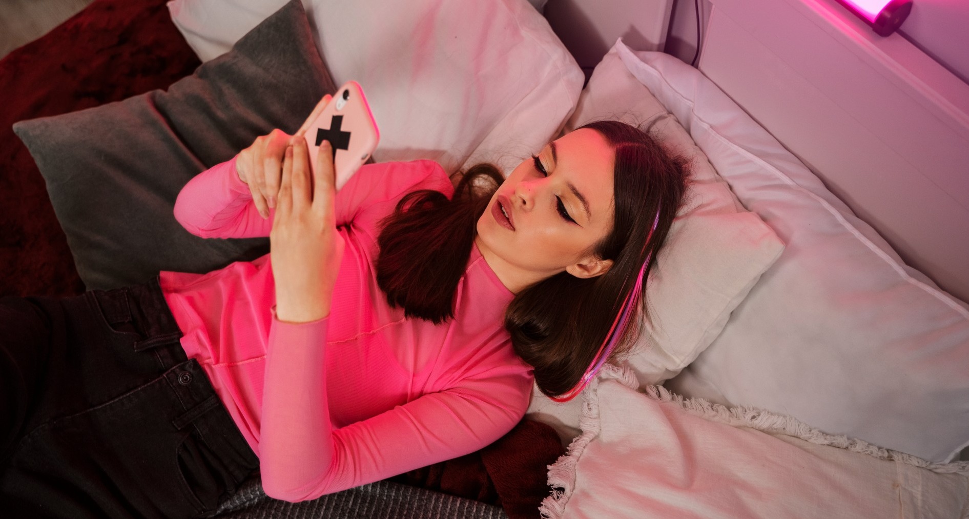 chica joven con teléfono móvil tumbada en una cama