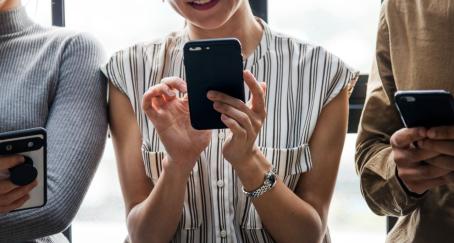 Tres personas jóvenes mirando sus teléfonos móviles