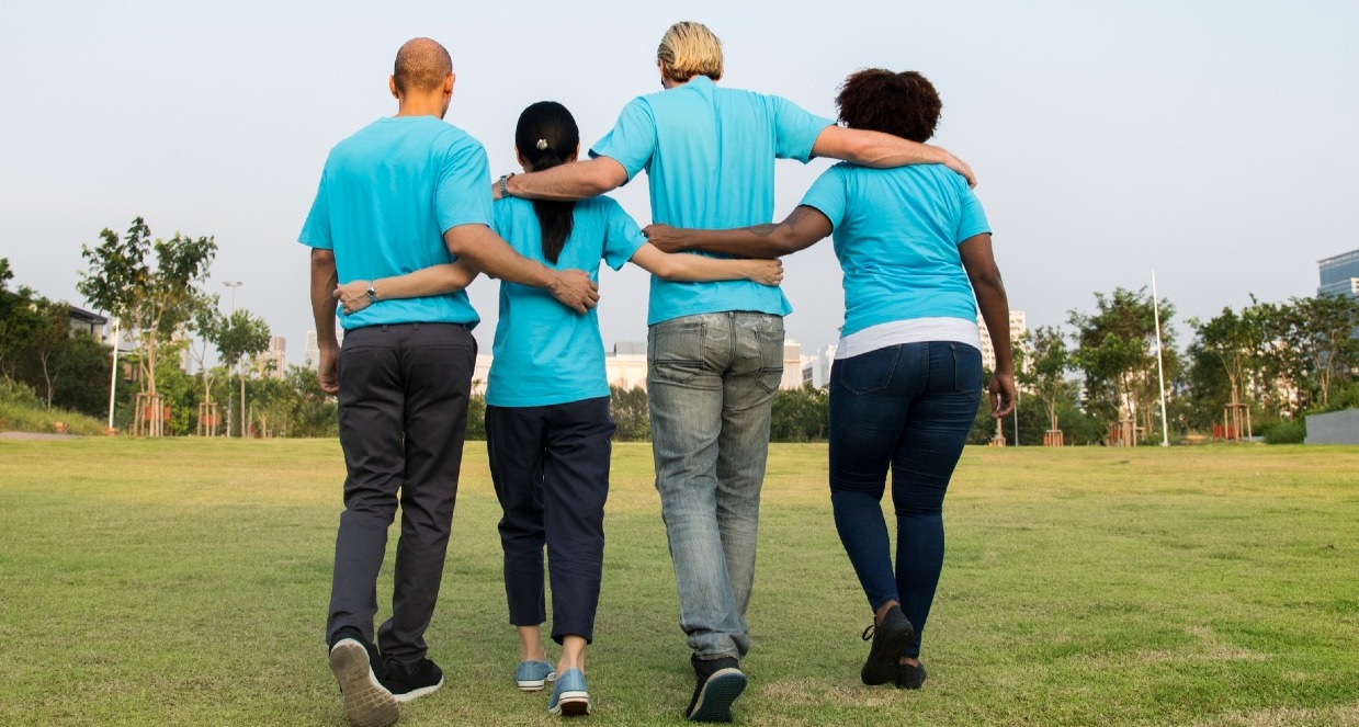 Un equipo de espaldas se abraza, vestidos todos con polos azules