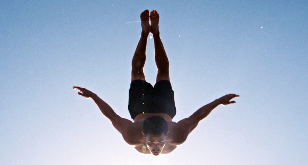 Un hombre haciendo un salto al agua con los brazos en cruz
