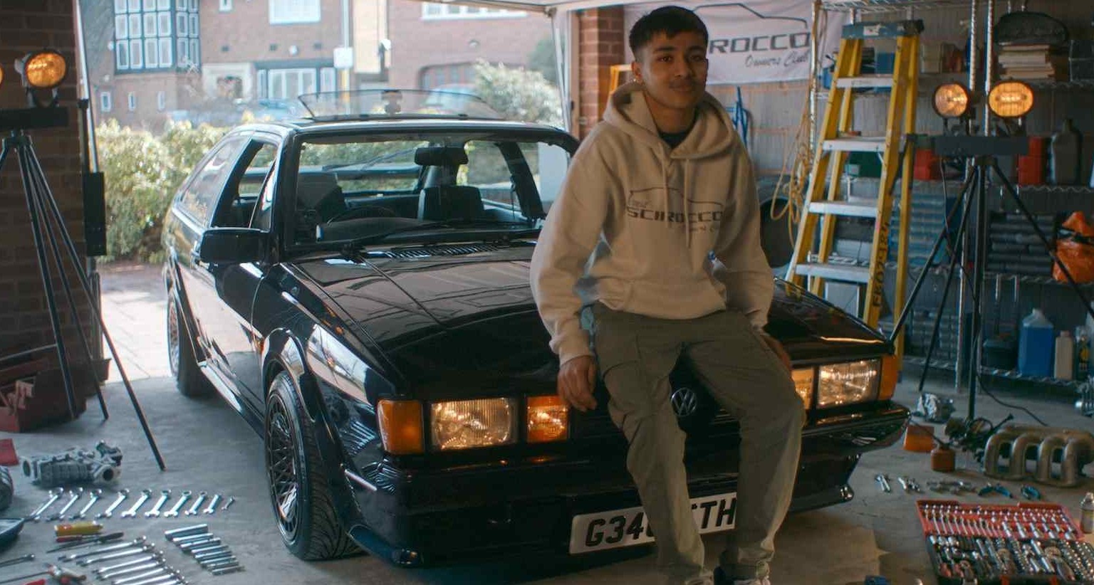 Un joven apoyado sobre un coche antiguo de Volkswagen