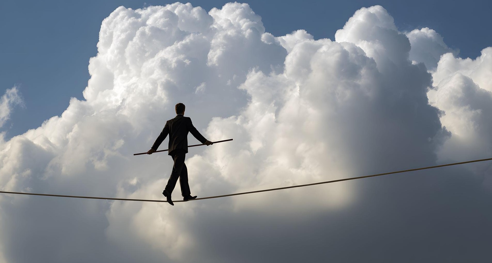 Hombre haciendo equilibrios sobre una cuerda con nubes de fondo