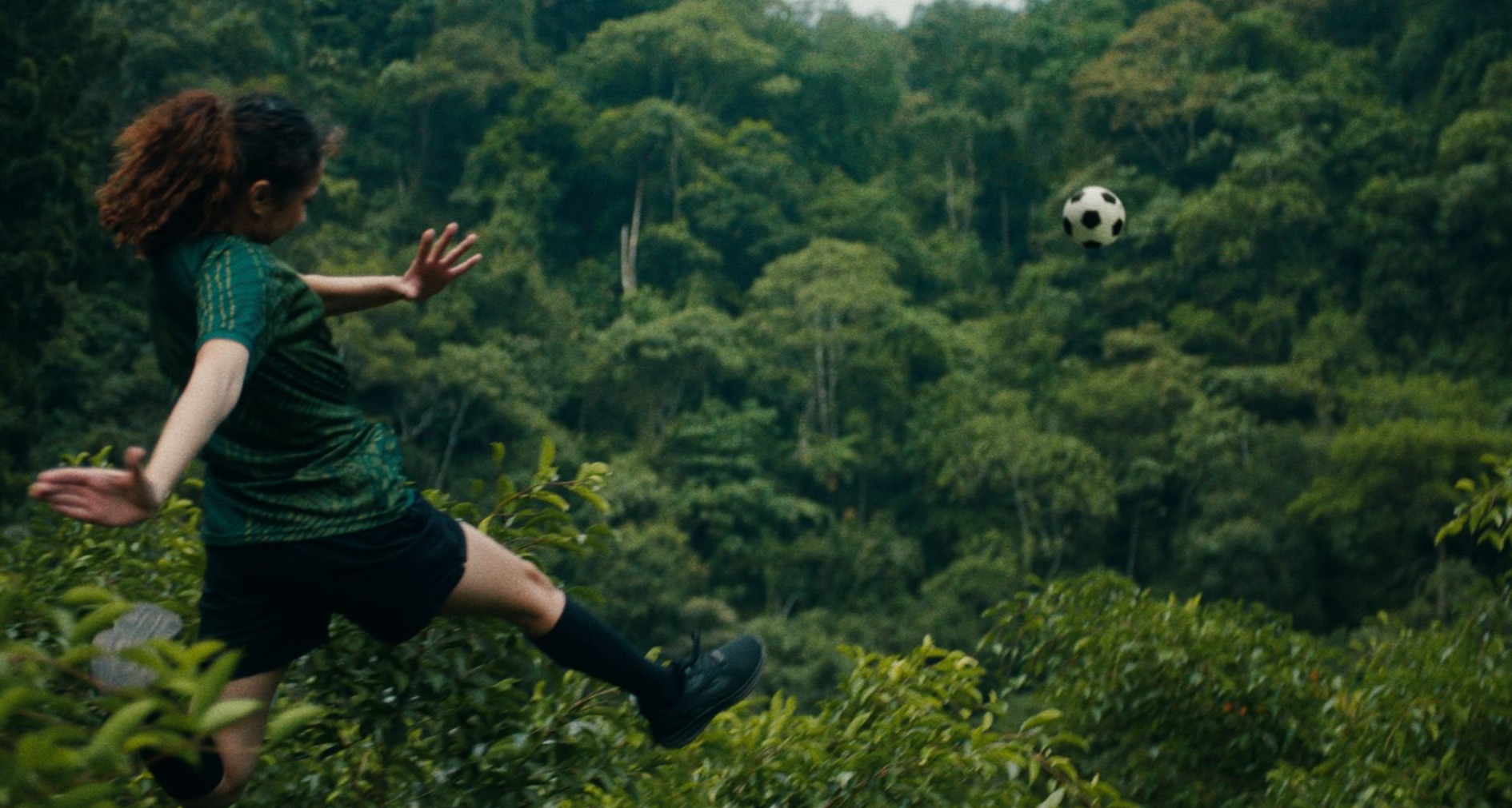 Una chica juega al fútbol sobre las copas de los árboles