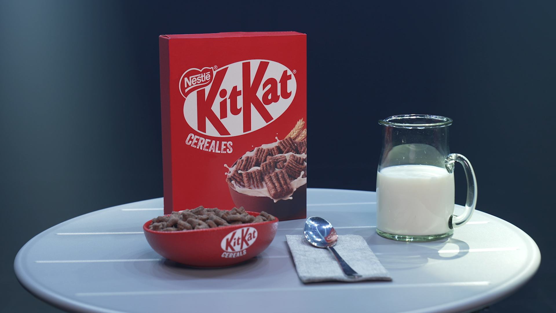 Bodegón la caja de KitKat Cereales, un bol con el producto y una jarra de leche. 