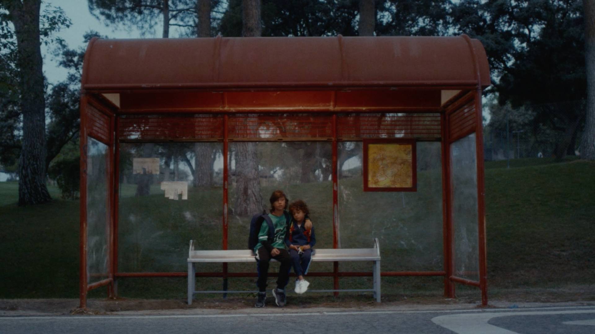 Imagen del spot: niños sentados en la parada del autobús.