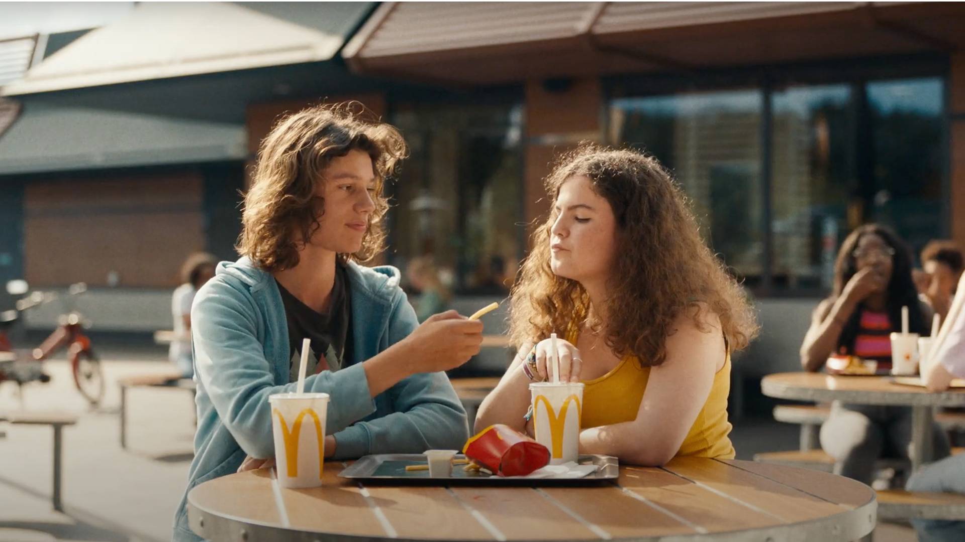 El chico le ofrece una patata frita a la chica en el McDonald's