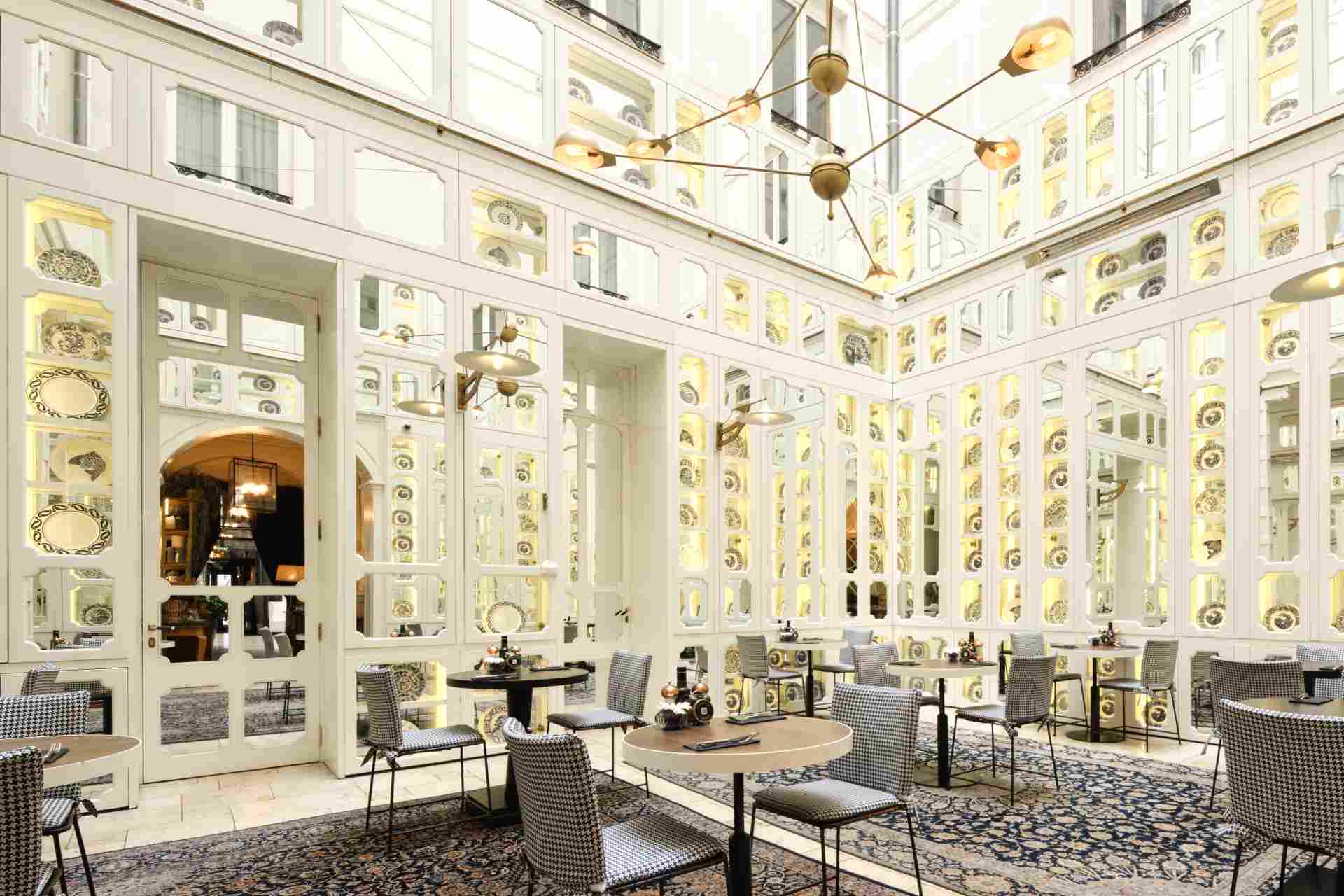Imagen de una estancia de uno de los hoteles decorada con estanterías con platos. Hay mesas y sillas al estilo de una cafetería.
